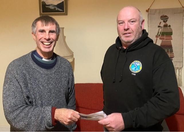 Tom hands a cheque to the local vicar
